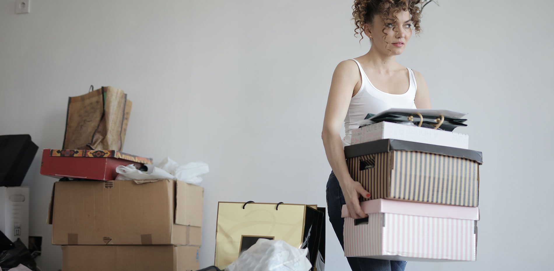 woman carrying stack of cardboard boxes